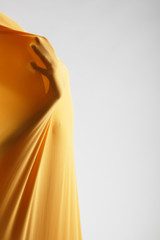 abstract hands, human arm inside yellow fabric, studio shot