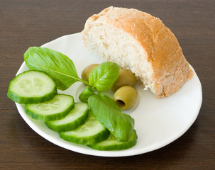 Slices of cucumber, olives, basil leaves and a piece of bread
