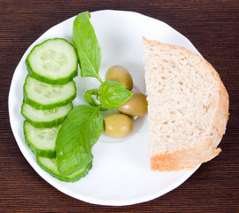 Fresh cucumber, olives, basil leaves and a piece of bread