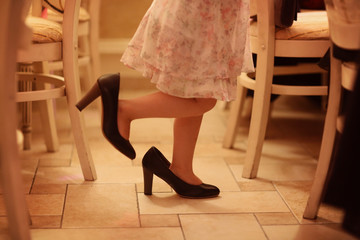 Legs of a girl playing with mothers shoes