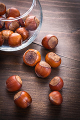 composition of hazelnutes in round glass and on vintage wooden b