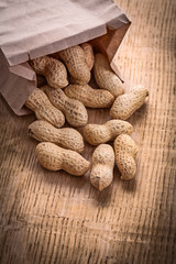 peanuts poured from paper bag on wooden board food and drink sti