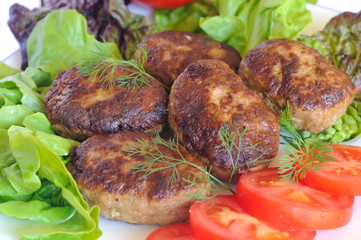 Cutlets with tomatoes and salad and dill on a white plate