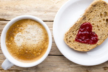 Fresh coffee. Grain slice of bread with jam heart shape.
