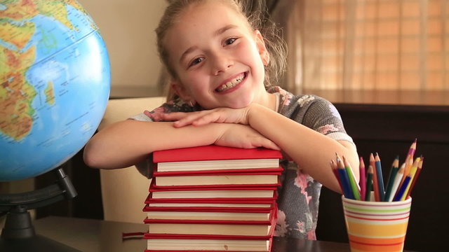 Elementary age girl posing on a stack of books.