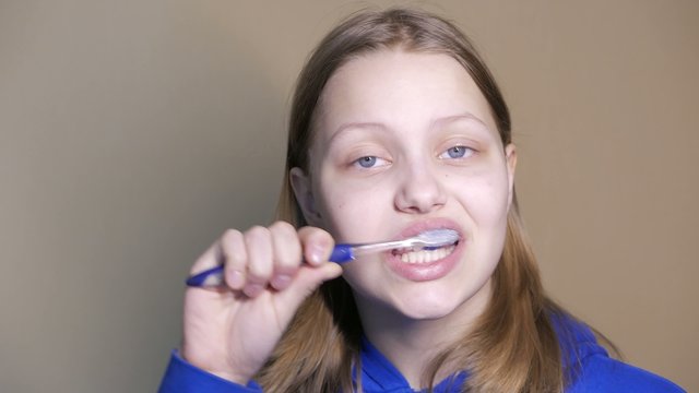 Unhappy teen girl brushing teeth