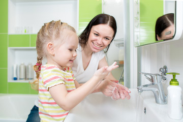 Happy mother and child washing hands with soap in bathroom