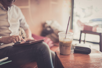 Fototapeta na wymiar Ice coffee in plastic glass with wallet in cafe with businessman