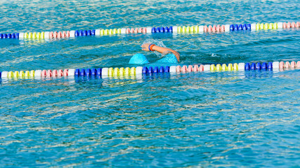 swimmer swimming crawl in blue water and wearing a blue cap