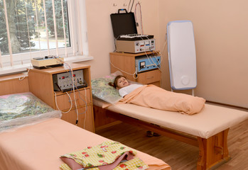 The little sick girl lies on a couch in a physiotherapeutic offi