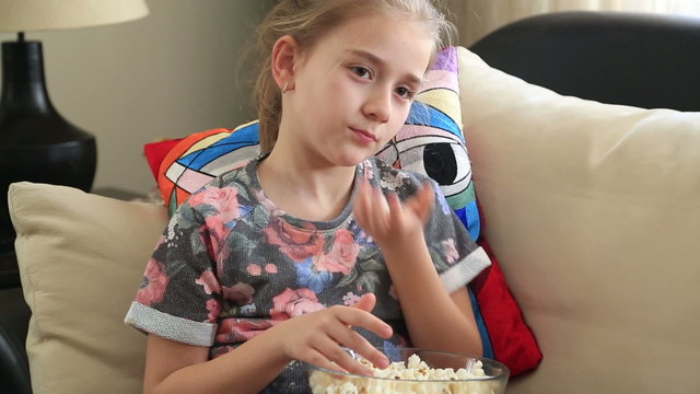 Little girl zapping and eating popcorn