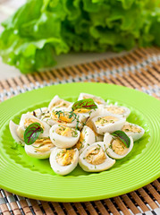 Boiled quail eggs halves on a green plate