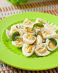 Boiled quail eggs halves on a green plate