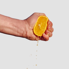 Man's hand squeezes the juice from the orange