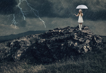 Girl with a white umbrella stands on the top of a mountain