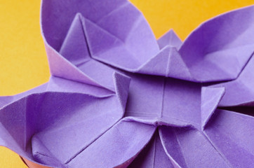 closeup of a purple paper origami flower on orange background