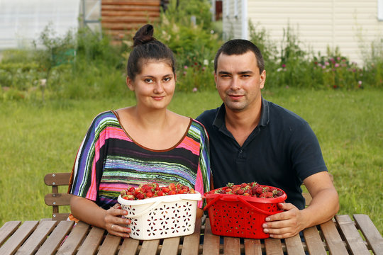 Happy man and woman with bucket of strawberry