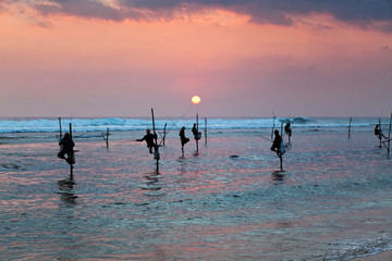 Fototapeta na wymiar Silhouettes of the traditional stilt fishermen at the sunset nea