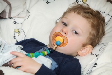boy with pacifier in bed