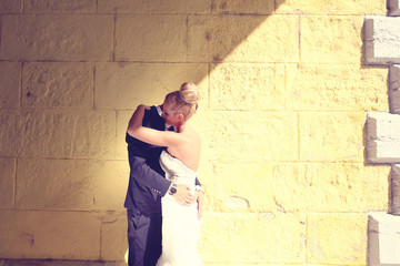 Obraz na płótnie Canvas Bride and groom faceing a yellow wall