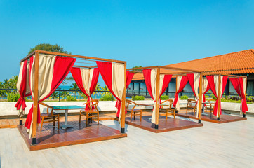 Pergolas with tables and chairs, red curtains on restaurant