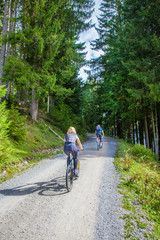 Obraz premium Mountainbiking auf einer Forststrasse durch den Wald am Berg