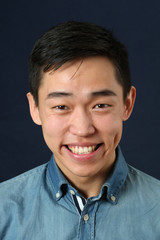 Laughing young Asian man looking at camera - obrazy, fototapety, plakaty