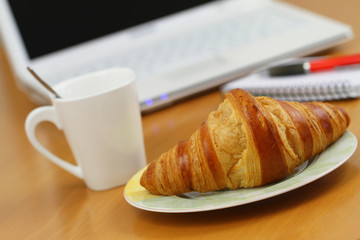 Butter croissant and coffee on office desk