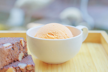 Ice cream in the cup with brownie on the wooden board