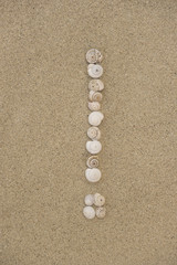 Ausrufezeichen aus Schneckenhäuschen im Sand