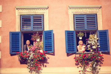 Bride and groom having fun from window of old house