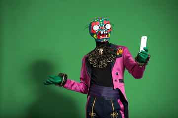 Actor in pink suit and mask zombie holding phone. - 81128192