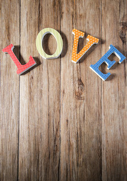 Wooden LOVE letters with vintage papers over wooden background a