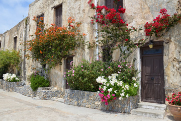 Stone wall with door, windows and beautiful flowers