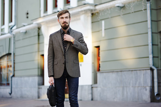 stylish man with a beard and mustache with a bag in hand on buil