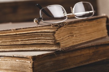 Antique. Old book and glasses on brown wooden planks background