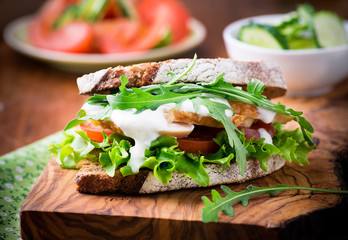 Rye toast sandwich with green leaf, tomato and chicken