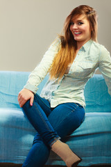 Fashionable girl wearing denim sitting on couch.