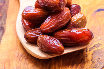 dried dates on spoon wooden background