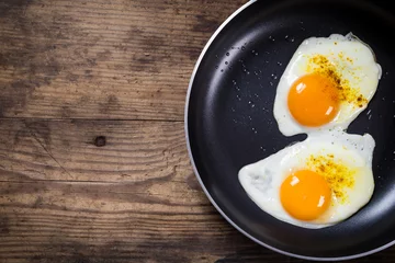 Photo sur Plexiglas Oeufs sur le plat deux œufs à la friture dans une casserole sur la table