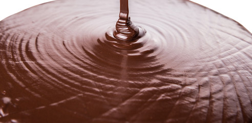 Pouring hot chocolate liquid over white background