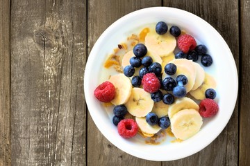 Cereal with blueberries, bananas, raspberries on wood background