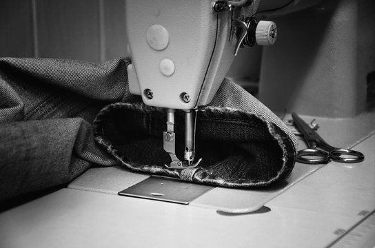 sewing machine and jeans in sewing workshop. monochrome