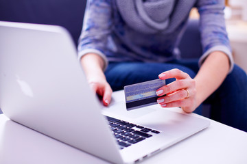Woman sitting at the desk, shopping with laptop and credit card