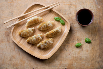 Pan fried gyoza dumplings with vegetables, rustic wooden surface