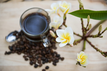 Cup of coffee with coffee beans on a beautiful flower.