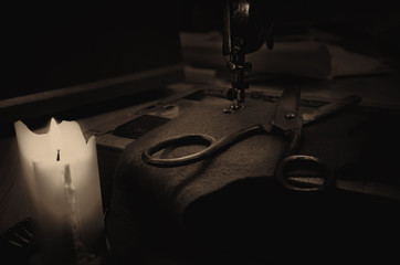old sewing machine, fabric and rusty scissors at the light candl