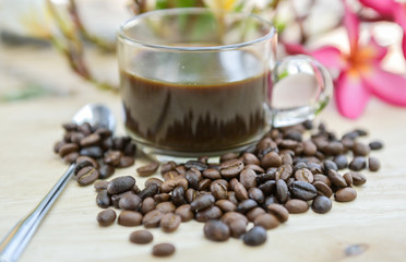 Cup of coffee with coffee beans on a beautiful flower.