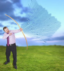 Businessman practicing archery with green field in background
