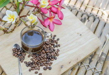 Cup of coffee with coffee beans on a beautiful flower.